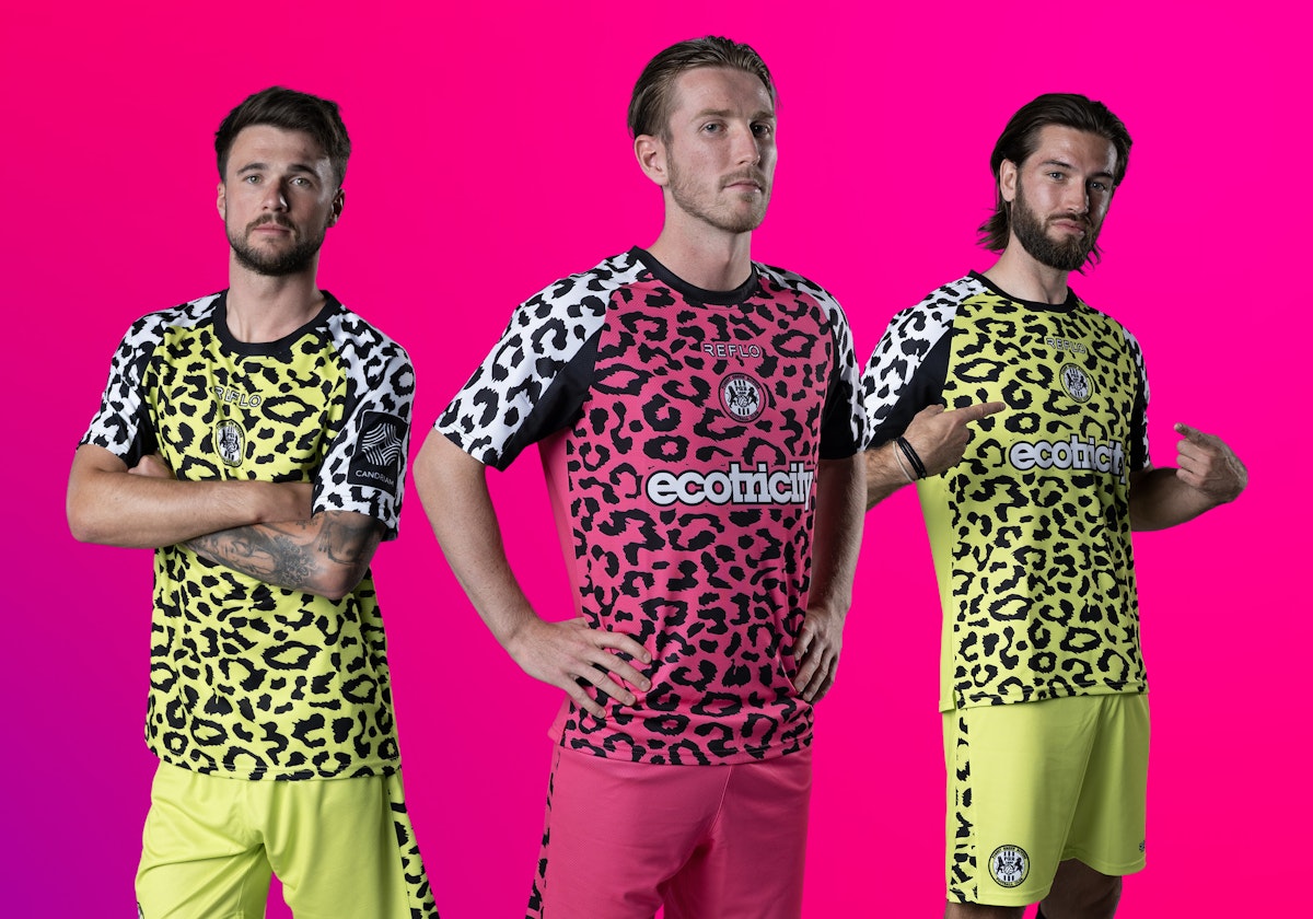 The new Reflo x Forest Green Rovers kit - two players wear the lime green home shirt and one wears the hot pink away shirt. 