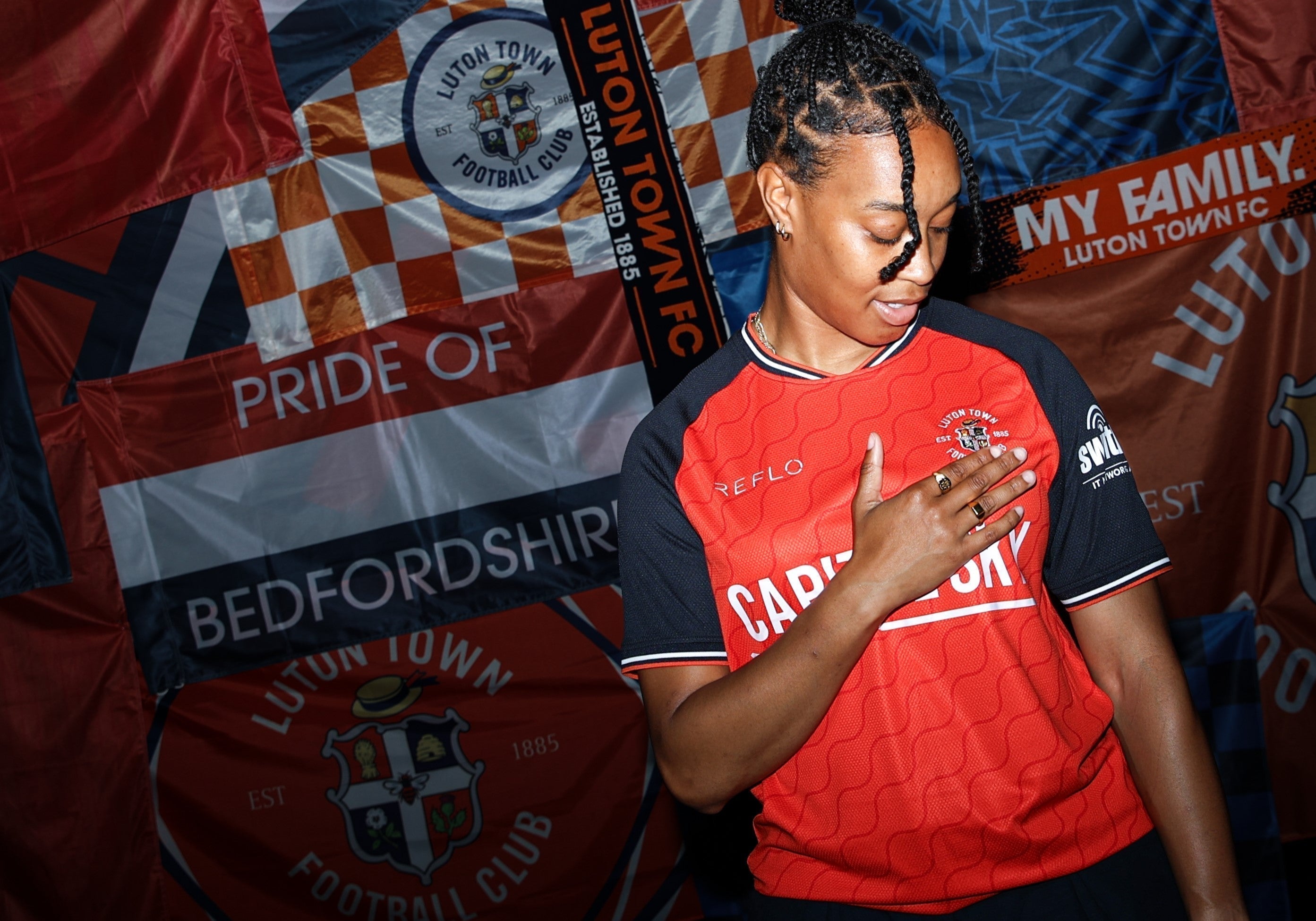 Luton Town FC player puts their hand over the club badge in the new Home Kit designed by Reflo for 25/26 season