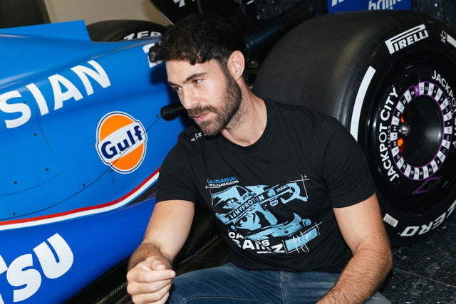 Model wears the new Atlassian Williams Racing Carlos Sainz black tee by the F1 car. 